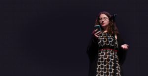 young woman reading from cell phone at mic